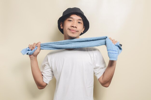 Gelukkige aziatische man met een helder wit t-shirt met zwarte hoed en een handdoek op een geïsoleerde achtergrond