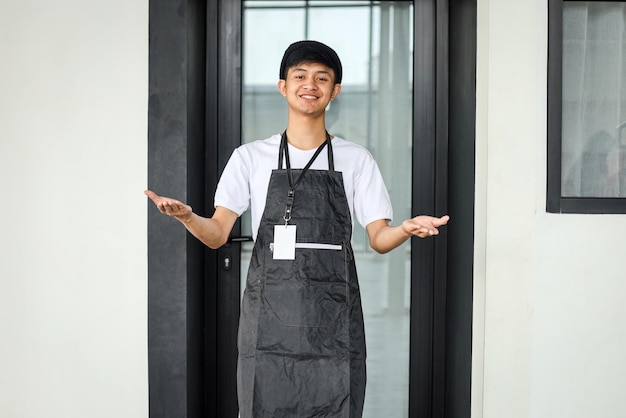 Gelukkige aziatische man met open armen in restaurant klaar om service of baan bij de voordeur te verwelkomen
