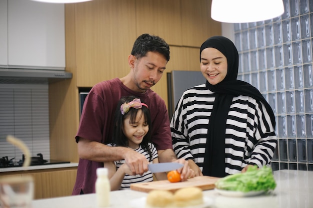 Gelukkige Aziatische moeder, vader en dochter koken samen in de keuken.