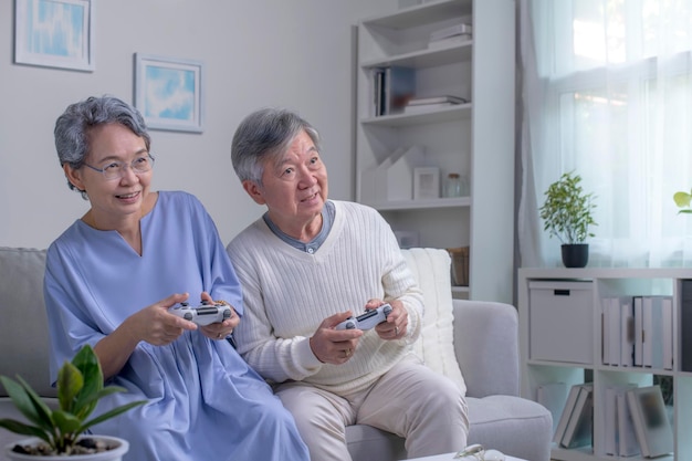 Gelukkige aziatische senior paar zitten samen op hun woonkamer tijdens het spelen van een videogame.