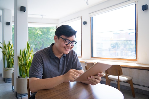 Gelukkige Aziatische tiener die smartphone en tablet gebruikt bij coffeeshop Aziatische man met tablet belt moeder