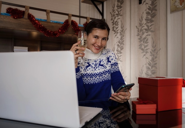 Gelukkige aziatische vrouw die blauwe sweater draagt die glas champagne houdt