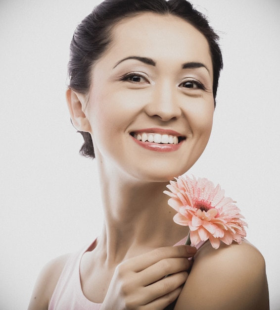 Gelukkige Aziatische vrouw die een roze gerbera houdt