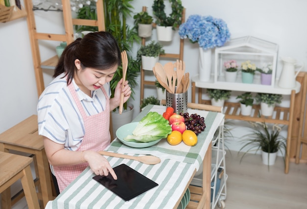 Gelukkige Aziatische vrouw die recept in de keuken maakt