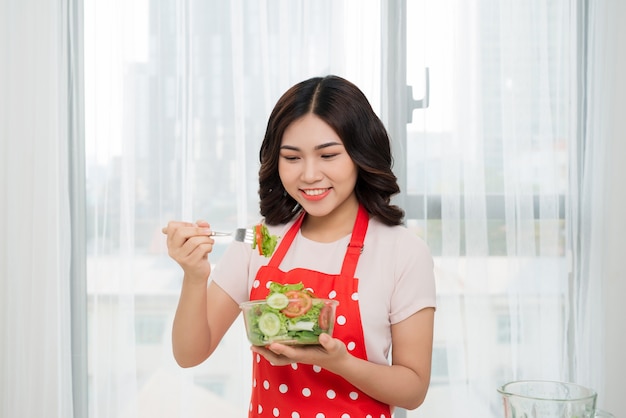 Gelukkige aziatische vrouw die salade uit glazen kom eet. hals eten.