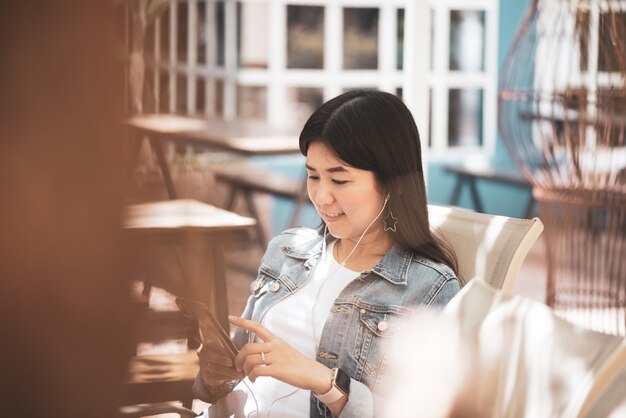 Gelukkige Aziatische vrouw die telefoon voor het luisteren van een muziek met behulp van.