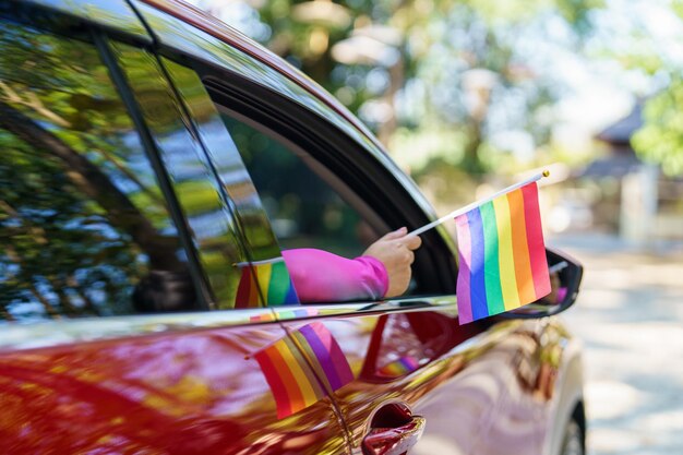 Gelukkige Aziatische vrouw steunt LGBT-trotsparade in auto met Rainbow of LGBTQ of LGBTQIA