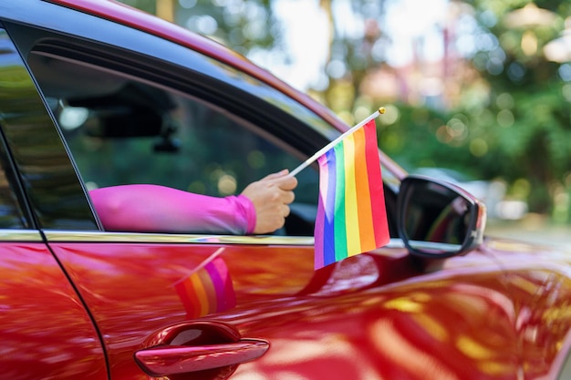 Gelukkige Aziatische vrouw steunt LGBT-trotsparade in auto met Rainbow of LGBTQ of LGBTQIA