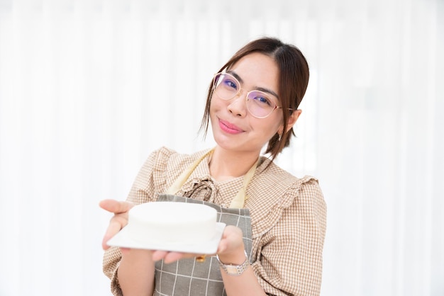 Gelukkige Aziatische vrouwelijke chef-kok maakt zoete dessert taart bakken bakkerij in over van bakkery in keuken restaurant