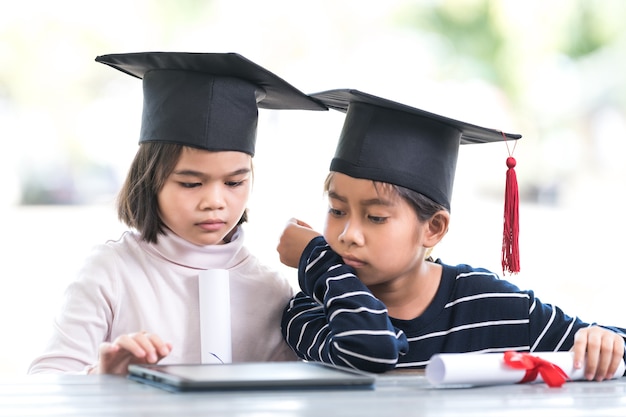 Gelukkige Aziatische vrouwelijke schooljongens met een afstudeerpet hebben een opgerold certificaat om het afstuderen te vieren. Afstuderen Viering Concept Stock Photo