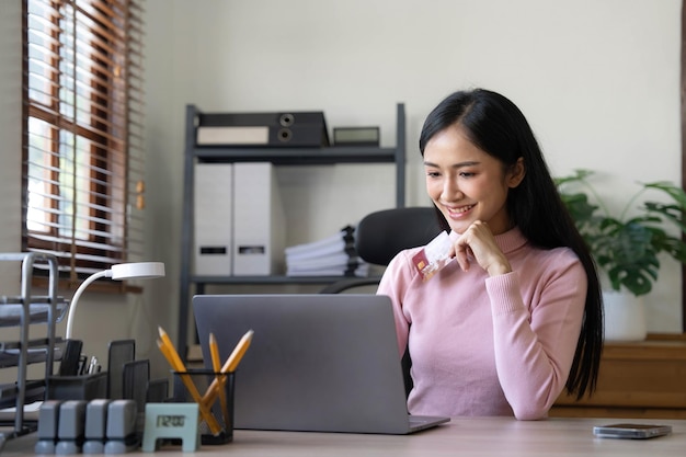 Gelukkige Aziatische zakenvrouw betaalt online met mobiele telefoon op kantoor