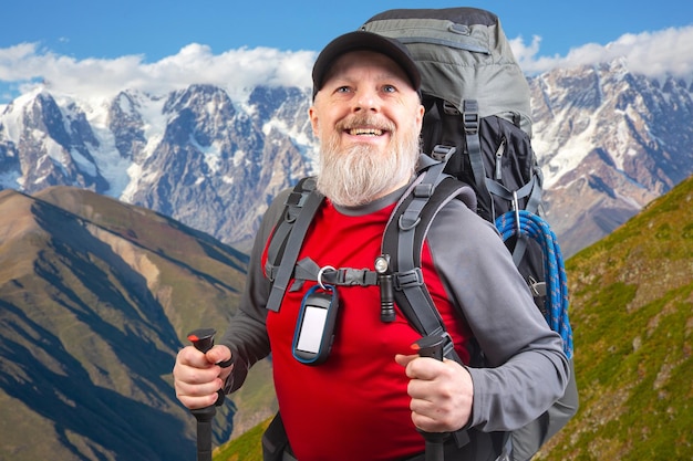 gelukkige baardige man reiziger met wandeluitrusting tegen de achtergrond van een berg