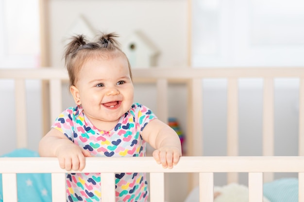 Gelukkige baby die thuis lacht in het kinderkamerportret van de baby in de wieg