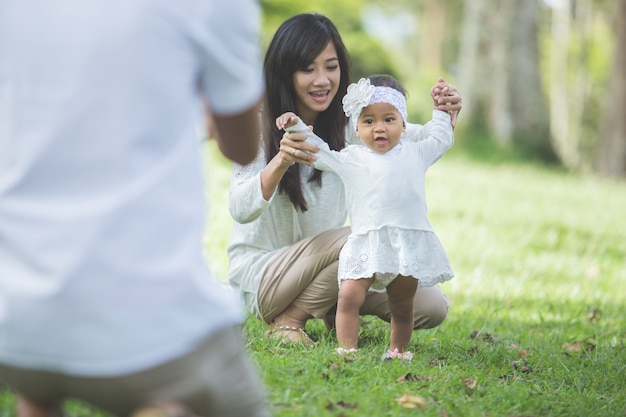 Gelukkige baby die zijn eerste stappen op een groen gras maakt