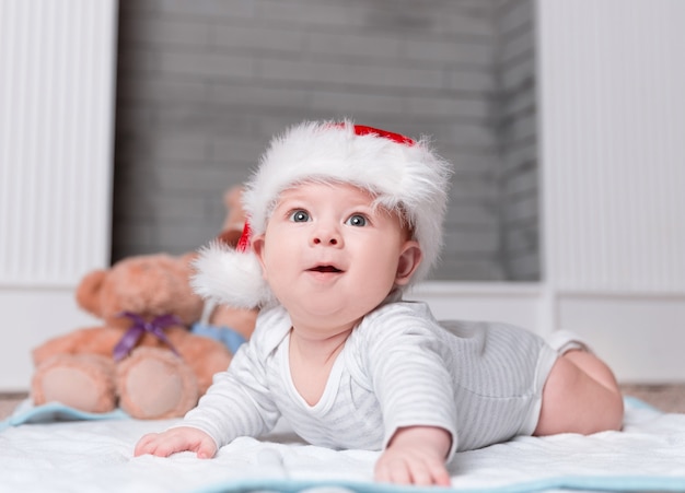 Gelukkige baby in de hoed van de kerstman op kerstavond. het concept van kerstmis