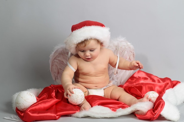 Gelukkige baby in een kerstkostuum en kerstmuts met vleugels