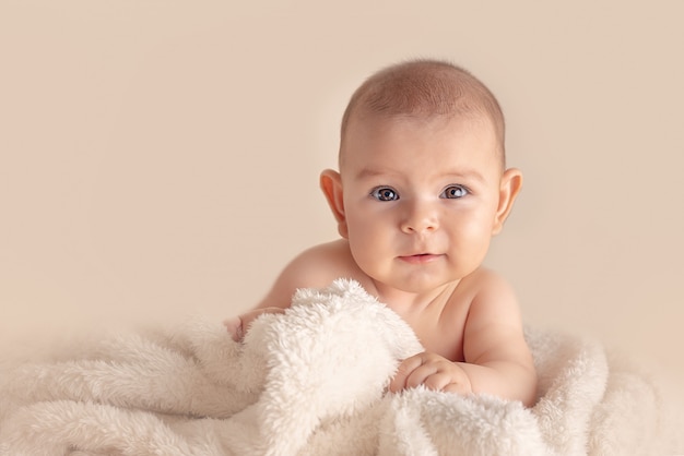 Gelukkige baby op eenvoudige achtergrond in studio op pluizige deken