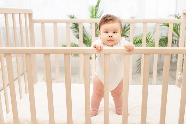 Gelukkige baby toont tong terwijl hij in de wieg staat