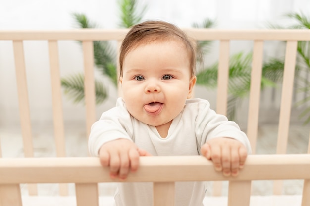 Gelukkige baby toont tong terwijl hij in de wieg staat