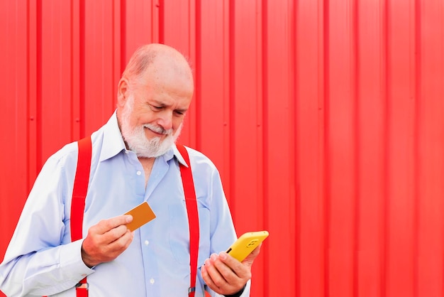 Foto gelukkige bejaarde man die een creditcard vasthoudt en naar een mobiele telefoon kijkt ouderen lifestyle en tech concept