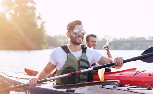 Gelukkige beste vrienden die plezier hebben op een kajak. Kajakken op de rivier. Twee vrienden in een boot die in de rivier vaart