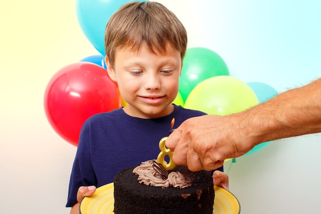 Gelukkige blanke jongen viert verjaardag door een chocoladetaart vast te houden