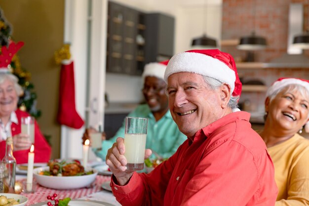 Gelukkige blanke senior man die glas vasthoudt en Kerstmis viert met een diverse groep vrienden