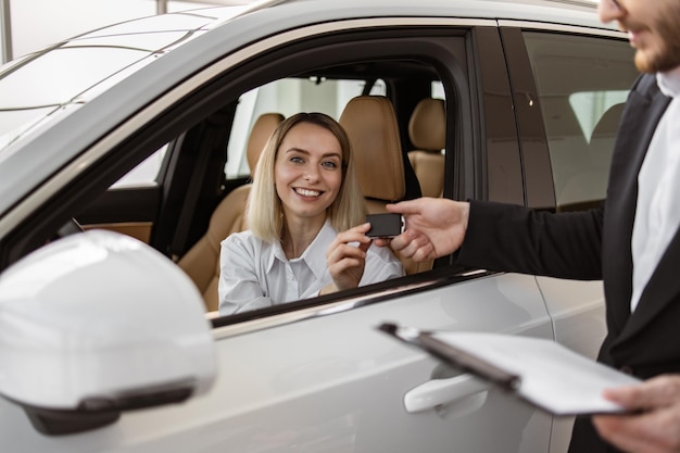 Gelukkige blanke vrouwelijke klant zit in een nieuwe moderne SUV.