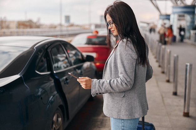 Gelukkige blanke vrouwenreiziger in de luchthaventerminal neemt een taxi