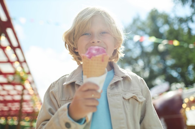 Gelukkige blonde jongen eten ijsje in zonlicht