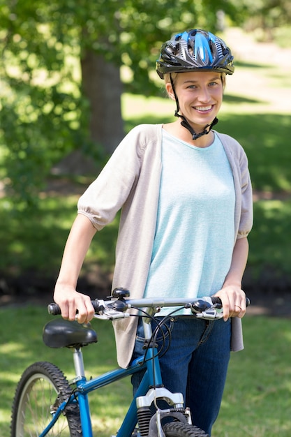 Gelukkige blonde met haar fiets in het park