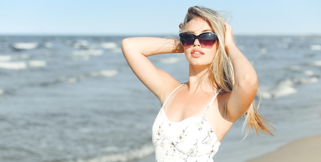 Gelukkige blonde vrouw in vrij geluk gelukzaligheid op oceaan strand staande met zonnebril