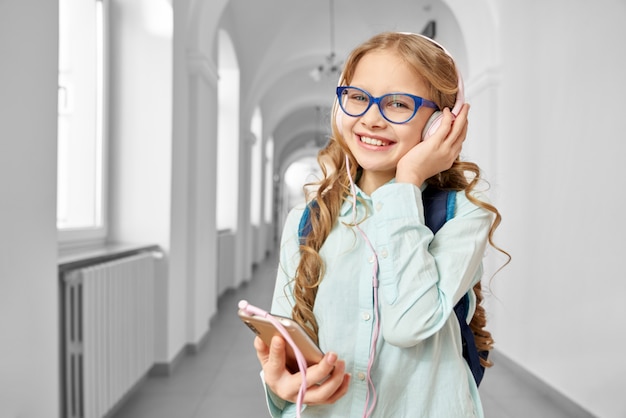 Gelukkige blondeschoolmeisje het luisteren muziek van hoofdtelefoons