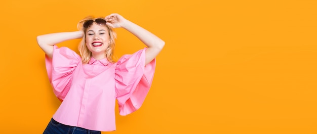 Gelukkige blondevrouw in roze blouse met zonnebril