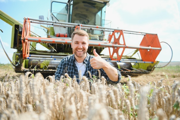 Gelukkige boer die trots in een veld staat maaidorserbestuurder gaat een rijke tarweoogst bijsnijden agronoom die een flanellen overhemd draagt en naar de camera kijkt op een landbouwgrond