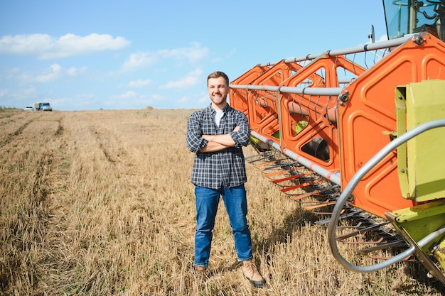 Gelukkige boer die trots in een veld staat Maaidorserbestuurder gaat een rijke tarweoogst bijsnijden Agronoom die een flanellen overhemd draagt en naar de camera kijkt op een landbouwgrond