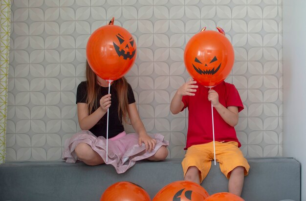 Gelukkige broer en zus op een halloween-feest. het concept van kinderen klaar voor een feestje. gekleed in enge kostuums, maskers en hoeden, met angstaanjagende gebaren. selectieve aandacht.