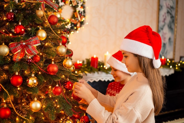 Gelukkige broers en zussen van meisjes en jongens die de kerstboom versieren Bereid je voor op het vieren van Kerstmis of Nieuwjaar