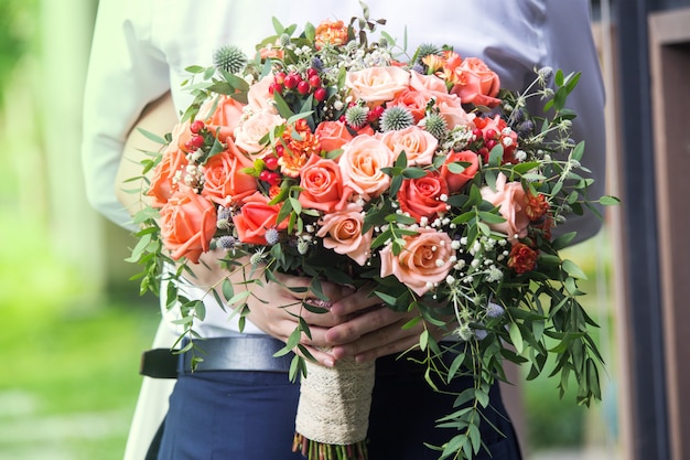 Gelukkige bruid en bruidegom in elkaars armen en een boeket van bloemen achter.