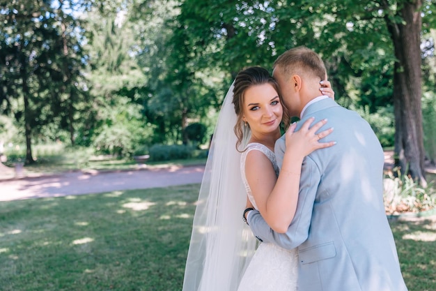 Gelukkige bruid en bruidegom in het park op hun trouwdag Een man en een vrouw knuffelen in het park na de ceremonie