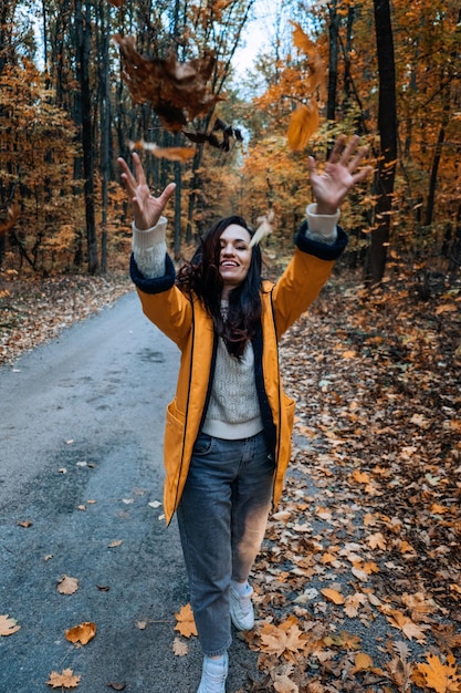 Gelukkige brunette vrouw met gele esdoorn herfstbladeren in herfstpark