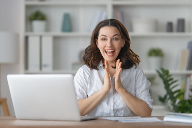 Gelukkige casual mooie vrouw die op een laptop op kantoor werkt