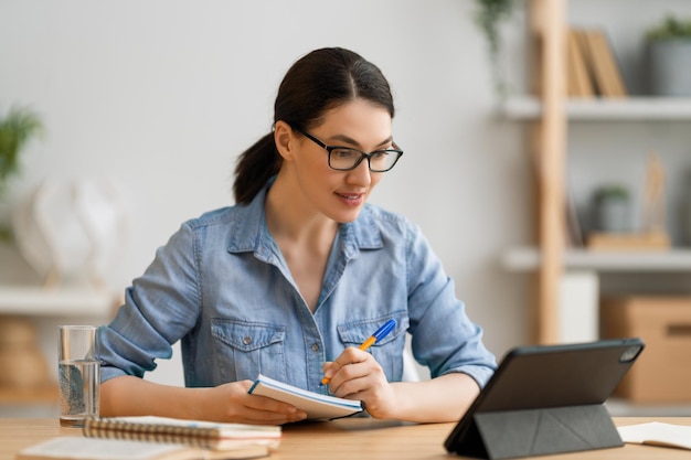 Gelukkige casual mooie vrouw die thuis aan een tablet-pc werkt.