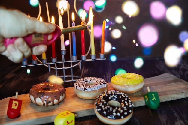 Foto gelukkige chanoeka en chanoeka sameach - traditionele joodse kandelaar met kaarsen, donuts en tollen op bruin houten achtergrond.