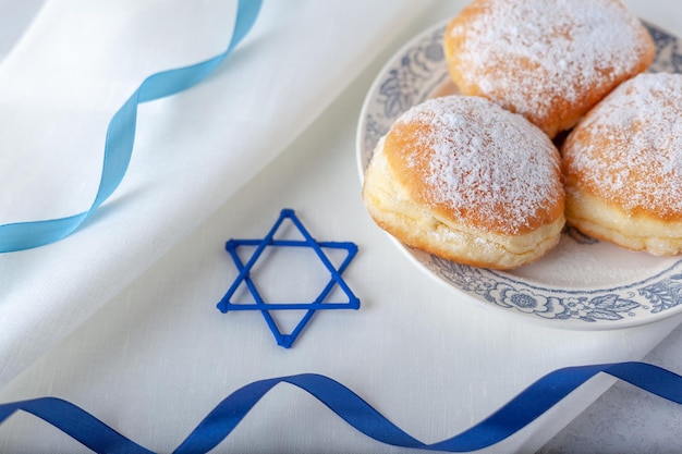 Gelukkige Chanoeka traditionele donuts sufganiyot op het witte servet met blauwe linten en David star