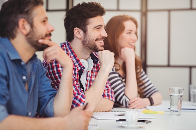 Gelukkige collega's die bij bureau in creatief bureau zitten