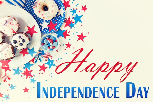 gelukkige dag van de onafhankelijkheid, viering, patriottisme en vakantie concept - close-up van cupcakes of muffins versierd met Amerikaanse vlaggen, donut en rood blauw snoep op plaat op 4 juli feest
