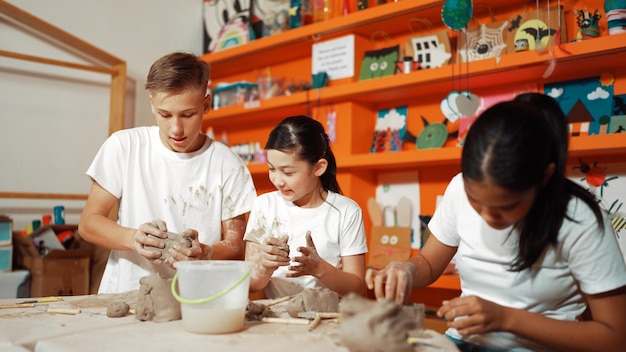 Gelukkige diverse middelbare scholieren modelleren klei in een pottenbakkerswerkplaats