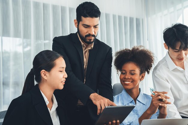 Foto gelukkige diverse zakenmensen werken samen en bespreken in het kantoor van een bedrijf professioneel en diversiteit teamwerk bespreken bedrijfsplan op het bureau met een laptop moderne multiculturele kantoorwerker concord