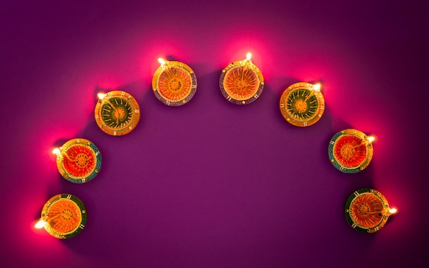 Foto gelukkige diwali clay diya lampen verlicht tijdens dipavali hindoe festival van lichten viering kleurrijke traditionele olielamp diya op paarse achtergrond